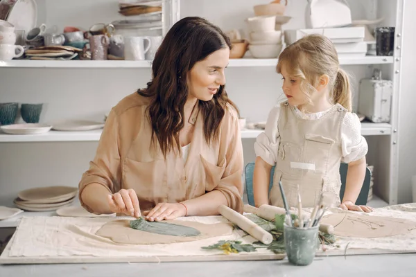 Kadın ve kız kil yoğuruyor. Aile, çömlekçilik atölyesindeki masada sanat ürünü yapıyor. Anne ve kızı..