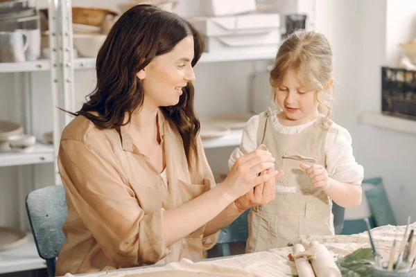 Kadın ve kız kil yoğuruyor. Aile, çömlekçilik atölyesindeki masada sanat ürünü yapıyor. Anne ve kızı..