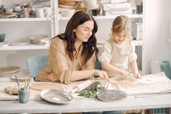 Kadın ve kız kil yoğuruyor. Aile, çömlekçilik atölyesindeki masada sanat ürünü yapıyor. Anne ve kızı..