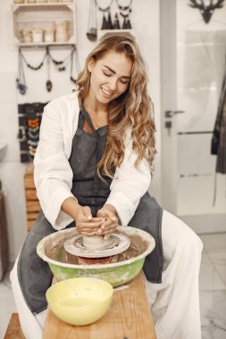 Stüdyoda çamurla çalışan kadın çömlekçi. Çömlekçiye su sıçrattı..