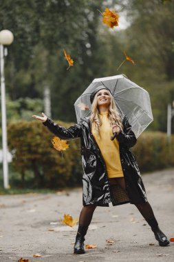 Kız yürüyor. Siyah ceketli kadın. Siyah şapkalı bir sarışın. Şemsiyeli kadın.