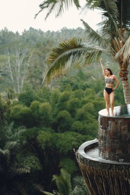 Yüzme havuzunda bir kadın var. Mayo giymiş bir kadın. Bali Endonezya 'da bir plaj kulübünde havuz kenarında dinlenen kız.