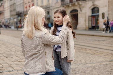 Genç anne kızını kucaklıyor. Kız yanağına Ukrayna bayrağını mavi ve sarı renklerle boyamış. Kadın ve kız Ukrayna 'yı savaşa karşı destekliyor.