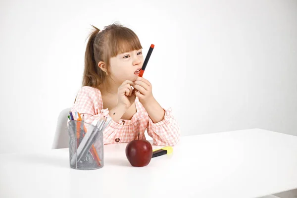 一个患唐氏综合征的阳光女孩坐在办公桌前 手里拿着一支钢笔 女孩一个人在家学习 残疾儿童教育概念 — 图库照片