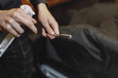 Berber dükkanı. Berberin yakın çekimi sakalını tıraş etmek için jilet tutuyor.