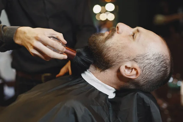 Man with a beard. Hairdresser with a client. Man with a brush.