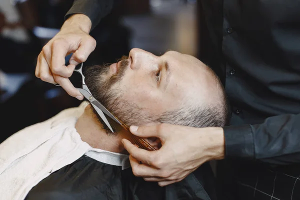 Man with a beard. Hairdresser with a client. Man with a comb and scissors