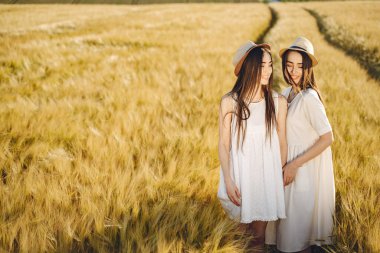 Buğday tarlasında iki güzel kız kardeş. Uzun, sağlıklı saçları olan iki güzel kız yazın doğanın tadını çıkarıyor..