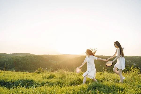 Buğday tarlasında iki güzel kız kardeş. Uzun, sağlıklı saçları olan iki güzel kız yazın doğanın tadını çıkarıyor..