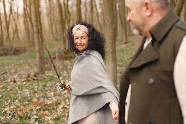 Ormandaki yaşlılar. İnsanlar yürür. Bahar çiçekli aile.