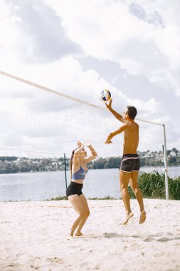 Spor ve aktif yaşam teması. Genç oyuncular voleybol oynar. Plaj oyun alanı.