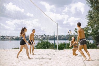 Spor ve aktif yaşam teması. Genç oyuncular voleybol oynar. Plaj oyun alanı.