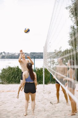 Spor ve aktif yaşam teması. Genç oyuncular voleybol oynar. Plaj oyun alanı.