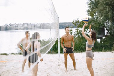 Spor ve aktif yaşam teması. Genç oyuncular voleybol oynar. Plaj oyun alanı.