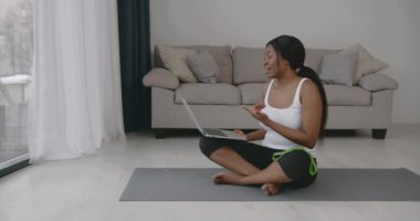 Sportif giyinen genç bir kadın video konferansında koçla konuşuyor. Danışmanlık, uzaktan eğitim..