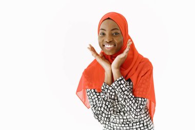 Hoş, dindar Müslüman bir kadının resmi. Nazik bir gülümsemesi, koyu sağlıklı bir teni var. Kafasına eşarp takıyor. Beyaz arkaplan üzerinde izole edilmiş.