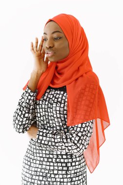 Hoş, dindar Müslüman bir kadının resmi. Nazik bir gülümsemesi, koyu sağlıklı bir teni var. Kafasına eşarp takıyor. Beyaz arkaplan üzerinde izole edilmiş.