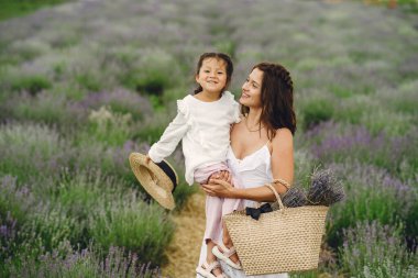 Lavanta arka planda küçük kızı olan bir anne. Güzel bir kadın ve çayır tarlasında oynayan sevimli bir bebek. Yaz günü aile tatili.