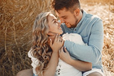 Buğday tarlasında oturan genç bir çiftin yakın çekimi. İnsanlar samanlıkta oturur ve kucaklaşır..