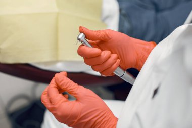 Dişçi aletleri alır. Koruyucu eldivenlerde doktor. Doktor matkap kullanıyor.