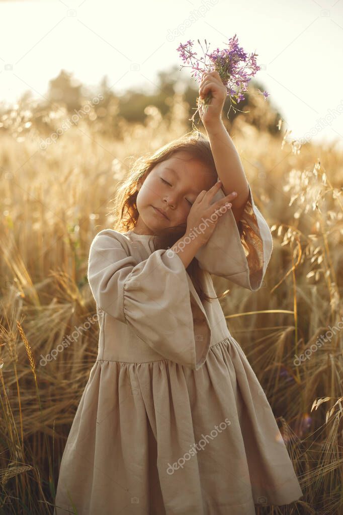 Child in a summer field. Little girl in a cute brown dress.