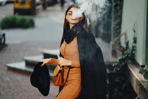 スタイリッシュな女の子がタバコを吸いながら街を歩いていると — ストック写真