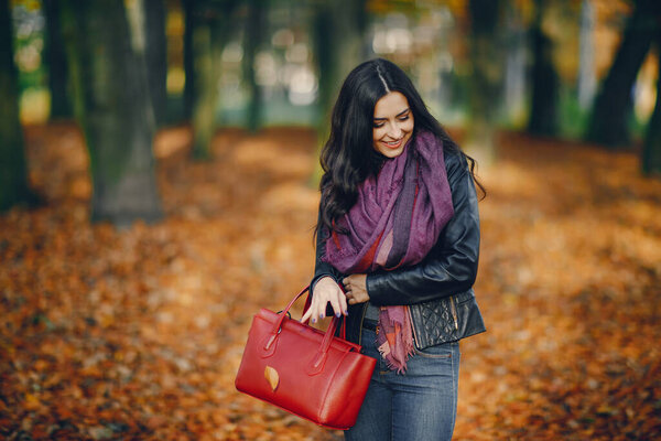 brunette girl relaxing at the park during autumn