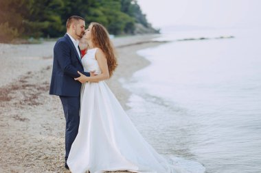 Sahilde genç kocasıyla beyaz elbiseli genç güzel uzun saçlı gelin