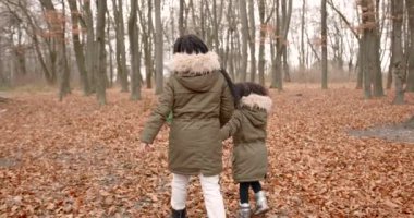 Ormanda sonbahar günü. Yaprakların üzerinde yürüyen ve çadırın yanında oynayan iki kız. Kamp, haftasonu, küçük kaşifler.