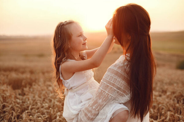 Family in a summer field. Sensual photo. Cute little girl. Woman in a white dress.