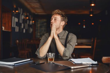 Man drinks whiskey. Businessman reads documents. Director in a shirt and suspenders.