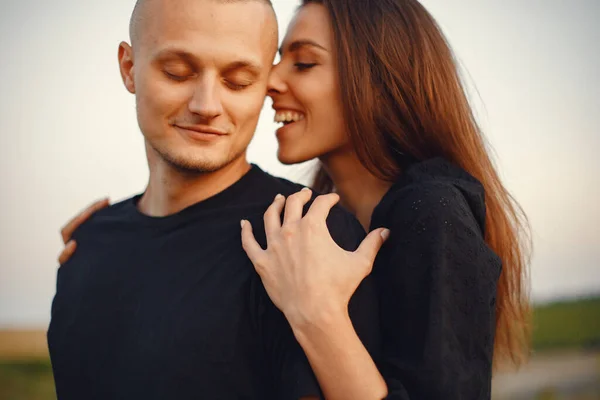 Couple in a field. Woman in a black blouse. Sunset background.