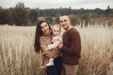 Küçük tatlı kızı olan bir aile. Kahverengi kazaklı baba. Sonbahar tarlasında bir aile