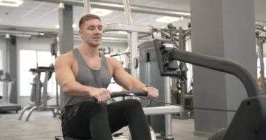 A young athlete in a gray T-shirt performs an exercise on his back in a modern gym. Training concept. Cut view