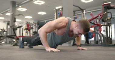 A young blonde athlete is squeezing off the floor in a modern gym. Maximum concentration on the exercise. Training concept