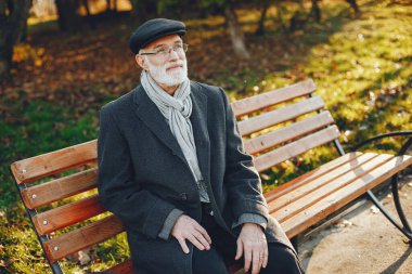 Yakışıklı dedesi bir sonbahar parkta. Yaşlı adam