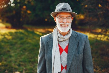 Yakışıklı dedesi bir sonbahar parkta. Yaşlı adam bir gri ceket ve şapka.