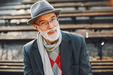 Yakışıklı dedesi bir sonbahar parkta. Yaşlı adam bir gri ceket ve şapka. Bankta oturan erkek