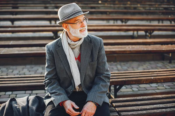 秋の公園でハンサムな祖父 グレーのジャケットと帽子の老人 ベンチに座っている男性 — ストック写真