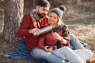Ağacın yanındaki çift. Bahar ormanındaki insanlar. Termosla eşleştir.
