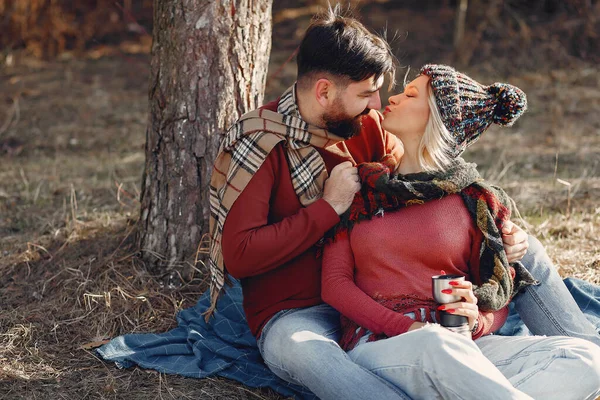 Couple by the tree. People in a spring forest. Pair with thermos.