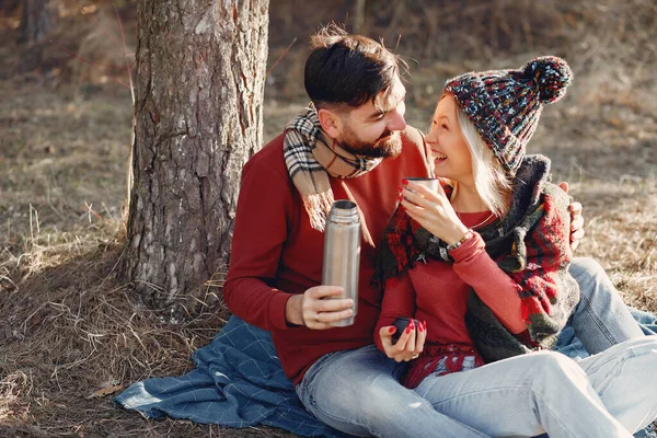 Couple by the tree. People in a spring forest. Pair with thermos.
