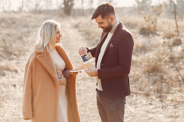 Woman in a brown coat. People in a spring forest. Family holding ultrasound.