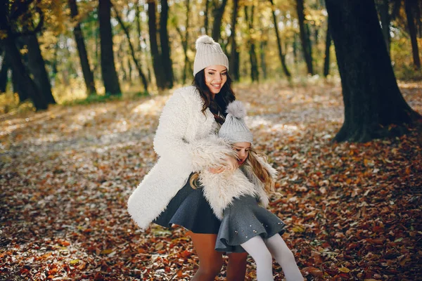 Beautiful mother with daughter. Family in a autumn park. Golden autumn