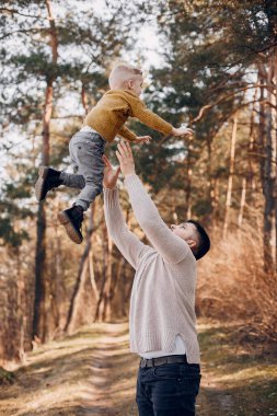 Yaz parkında aile. Kahverengi kazak giyen bir baba. Sevimli küçük oğlu