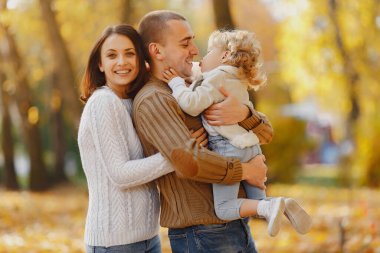 Küçük tatlı kızı olan bir aile. Kahverengi kazaklı baba. Sonbahar tarlasında bir aile
