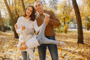 Küçük tatlı kızı olan bir aile. Kahverengi kazaklı baba. Sonbahar tarlasında bir aile