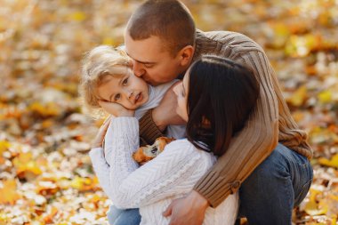 Küçük tatlı kızı olan bir aile. Kahverengi kazaklı baba. Sonbahar tarlasında bir aile