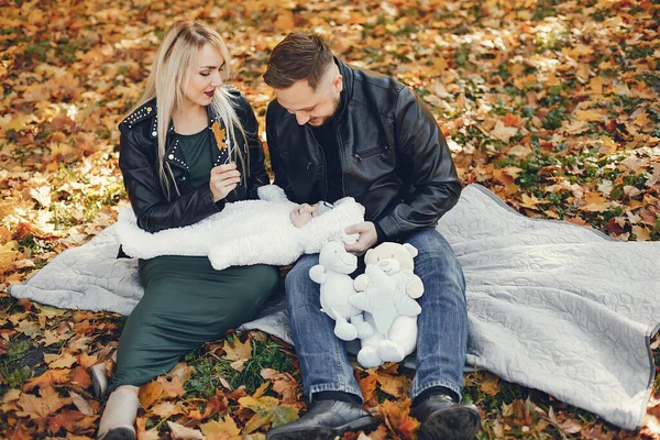 Family in a autumn park. Woman in a black jacket. Cute newborn little girl with parents