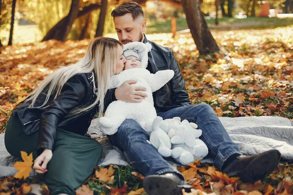 Family in a autumn park. Woman in a black jacket. Cute newborn little girl with parents